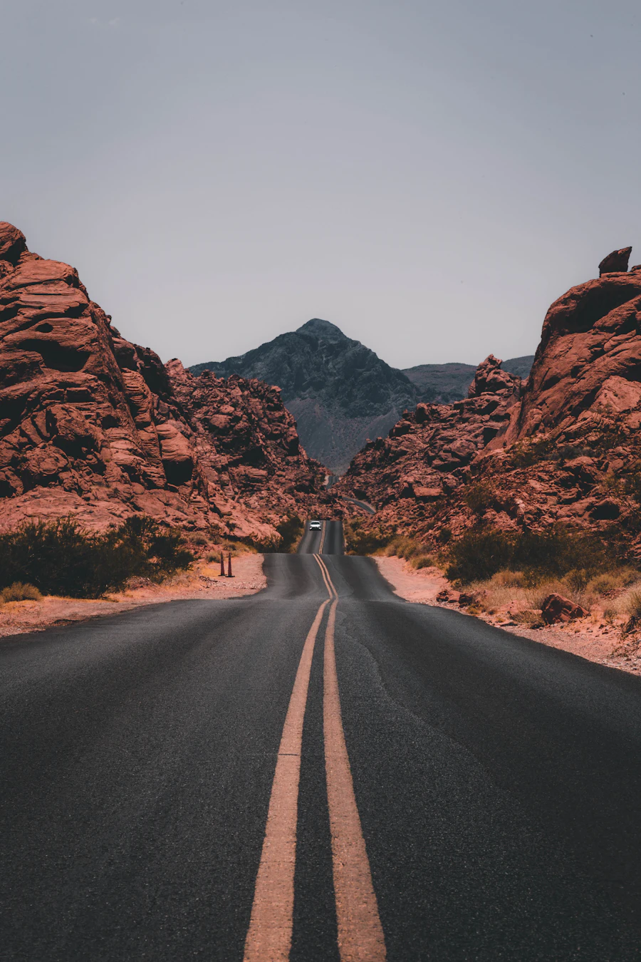 Empty road running between red rock mountains