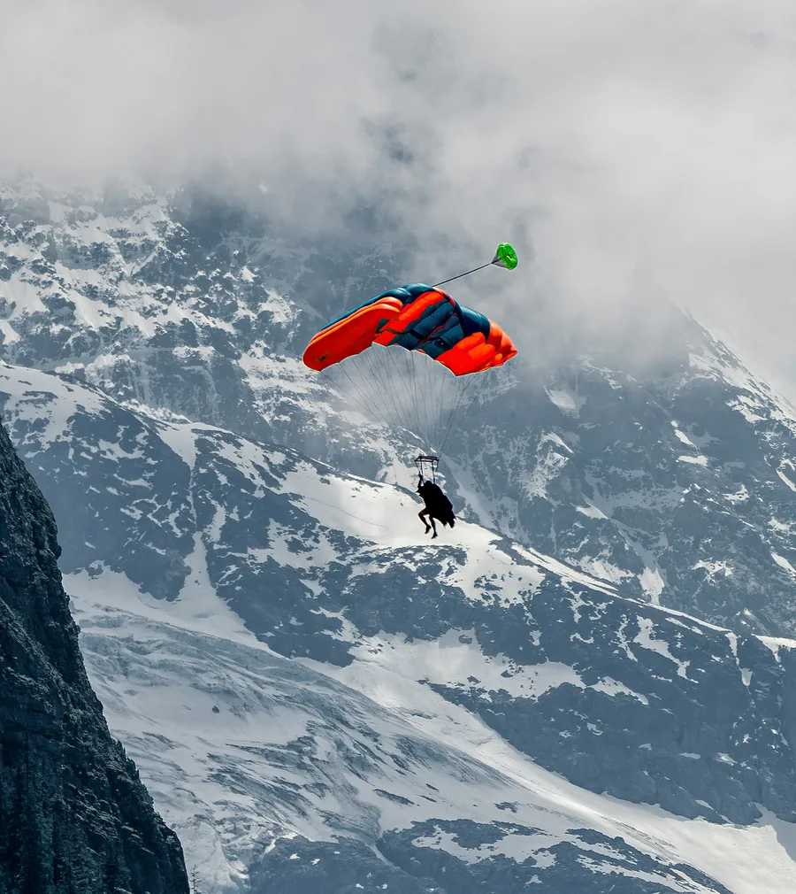 Parachutist gliding over snowy mountains